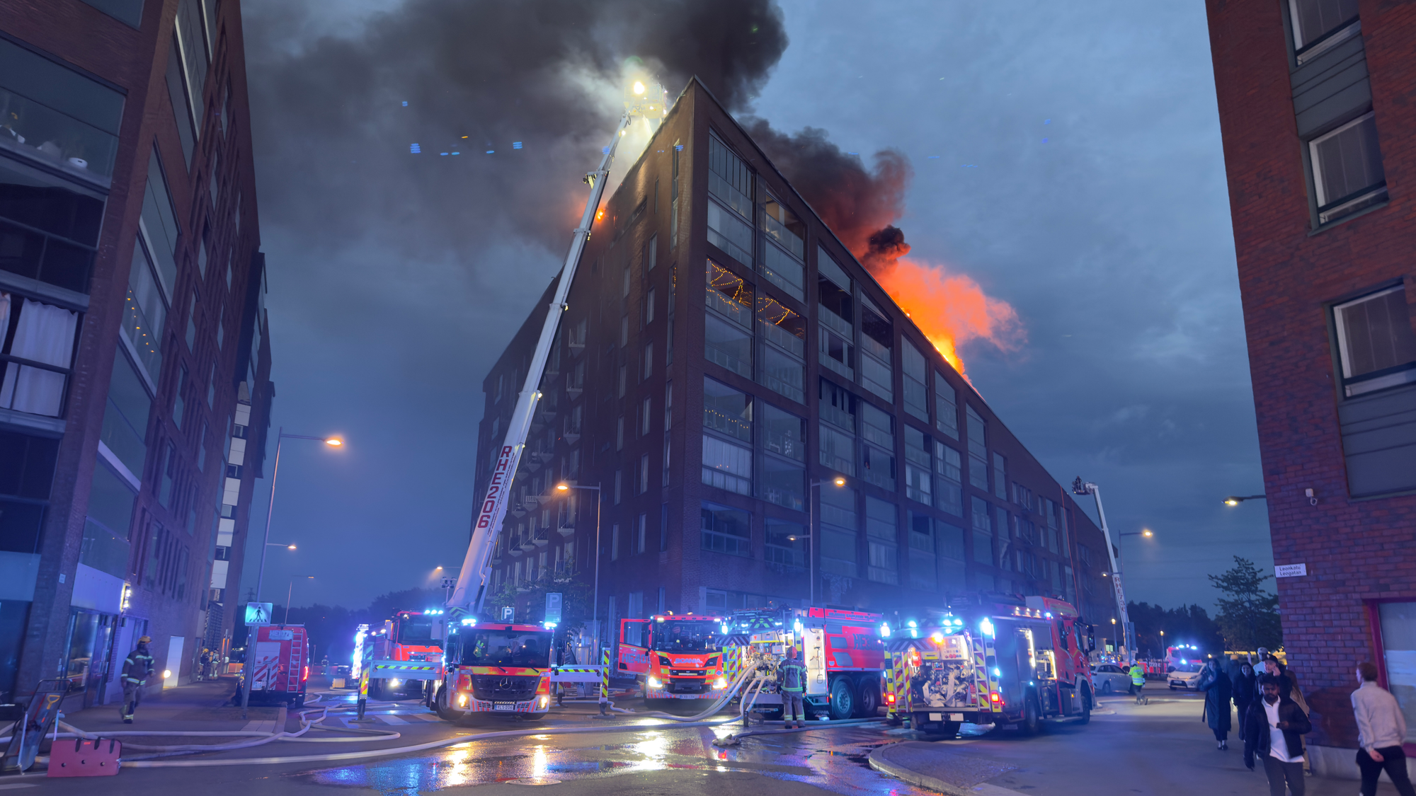 Flames and heavy smoke rising from the roof of the apartment building in Kalasatama