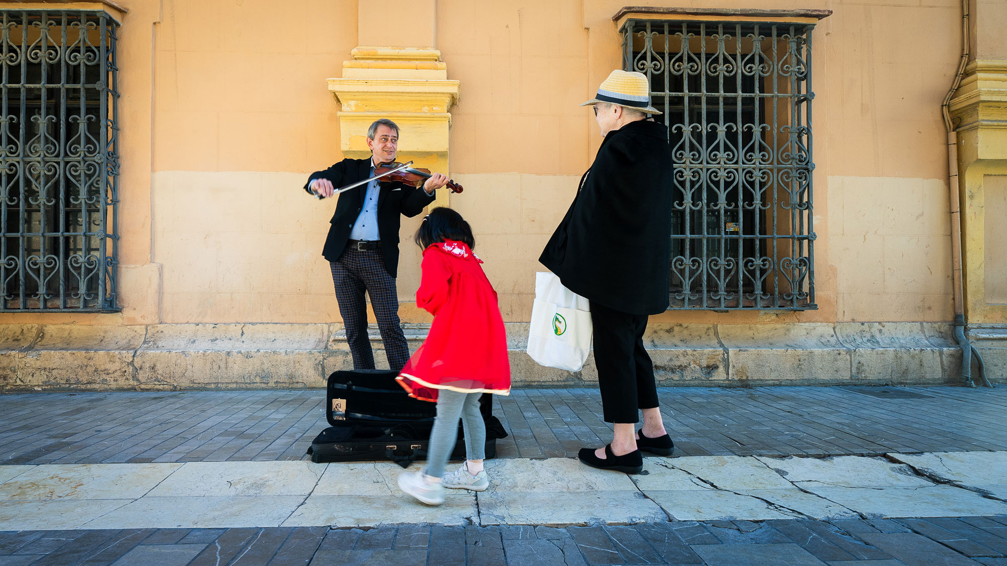 The elderly woman singing along with the violinist